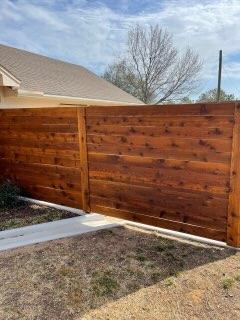 Reddish-stained horizontal cedar privacy fence with matching gate in Decatur, TX