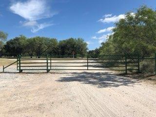 Green pipe entrance gate on a gravel ranch driveway near Decatur, TX