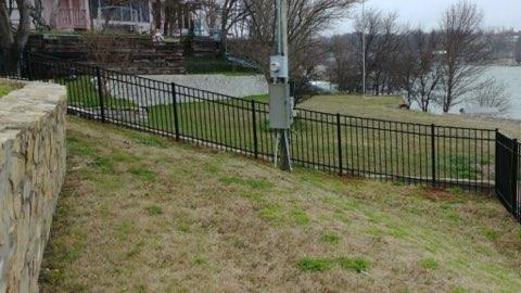 Ornamental iron fence along a lakeside stone retaining wall near Decatur, TX