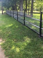 Black pipe and wire perimeter fence along a tree line in Wise County